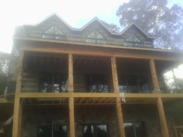 Dormers and porch framing on a large log home under construction — Roof Coating work by our crew in Milltown