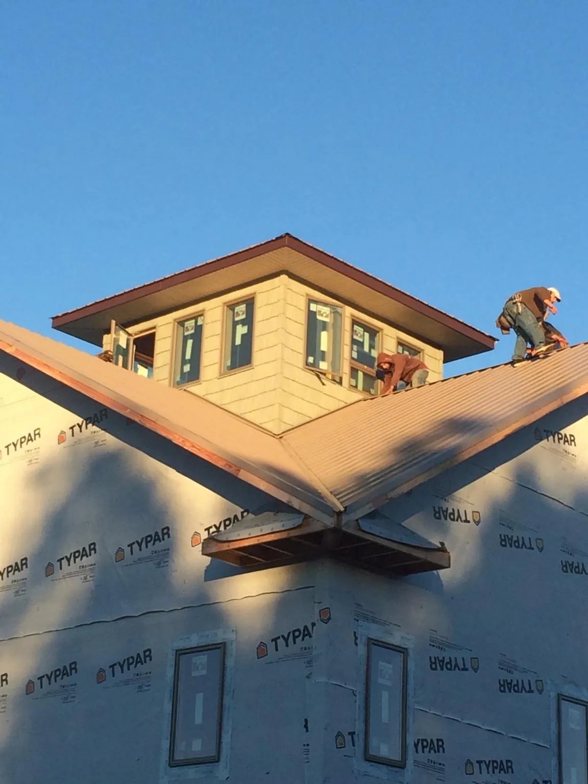 Roofers working around a rooftop cupola on a new metal roof at sunset — Roof Waterproofing in Milltown by Roofing Brothers